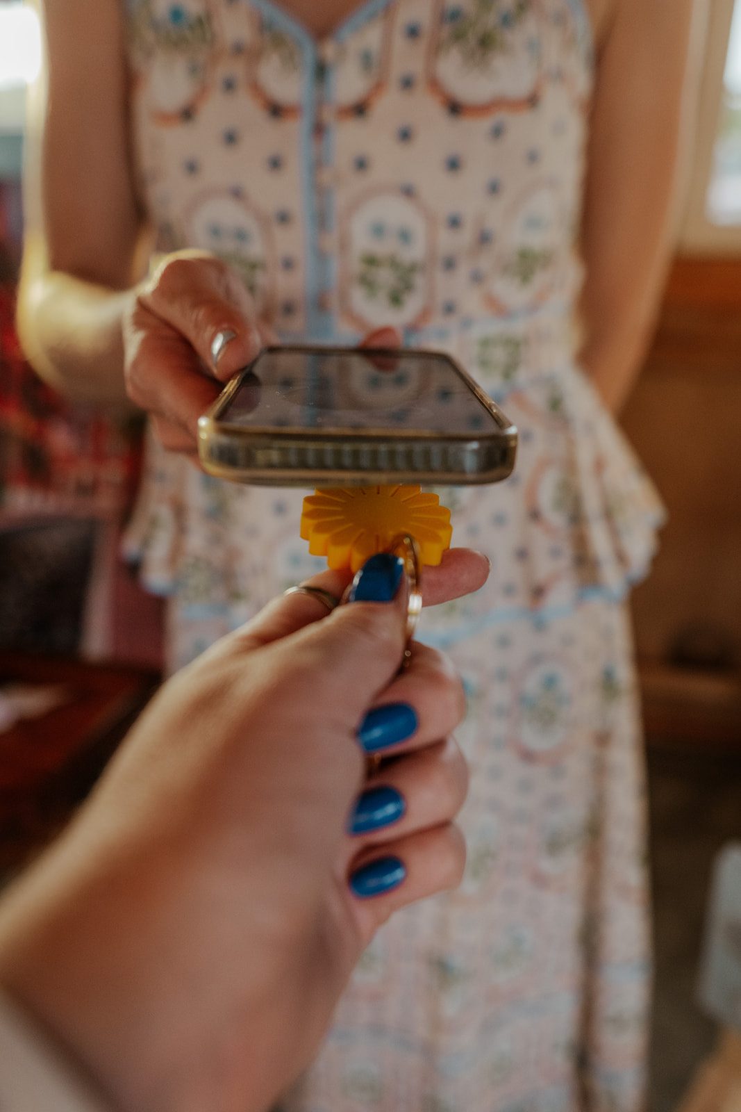 A sunflower keychain held to a phone